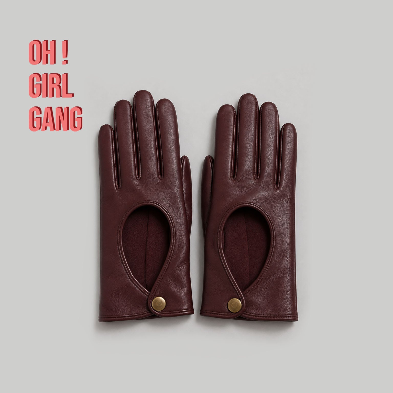 Pair of genuine leather driving gloves in burgundy, white, black, featuring an elegant open-back teardrop cutout with snap-button closure. Soft premium leather with a classic vintage-inspired design, displayed on a light grey background.