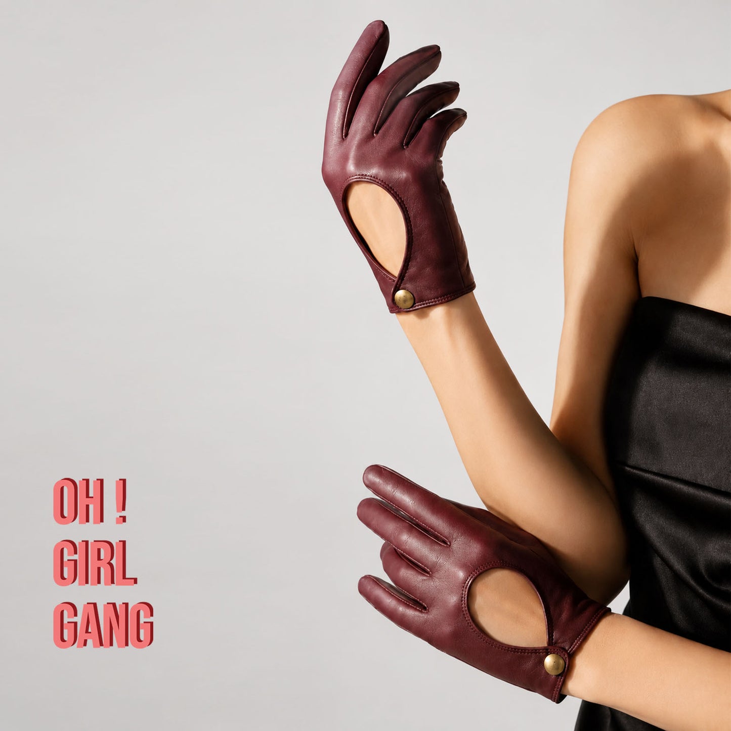 Pair of genuine leather driving gloves in burgundy, white, black, featuring an elegant open-back teardrop cutout with snap-button closure. Soft premium leather with a classic vintage-inspired design, displayed on a light grey background.